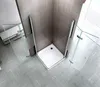 A corner shower cabin with glass doors and a white shower tray, set in a modern bathroom with tiled walls and a patterned floor. Produktbild-Vorschau