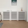 A white radiator cover is shown in a room with a light-colored wall and wooden floor. Náhľad obrázku produktu
