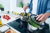 A person is cooking in a modern kitchen, with pots on a stovetop. Podgląd zdjęcia produktu