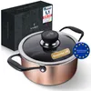A copper pot with a glass lid and black handles, placed next to its packaging box. There are several promotional stickers on the pot and the box. Produktbild-Vorschau