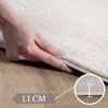 A hand is shown pressing down on the edge of a carpet, demonstrating its thickness. Produktbild-Vorschau