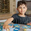 A young boy is sitting at a table, playing a card game. Anteprima dell’immagine prodotto