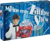 The image shows the packaging of a children's magic show toy set. A young boy dressed as a magician is featured prominently on the box, holding a magic wand. The packaging is designed with a starry blue background and bold text announcing the product name. Podgląd zdjęcia produktu