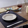 A table setting with placemats, plates, cutlery, bread, butter, and a glass of wine. Anteprima dell’immagine prodotto