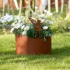 A rusty metal planter with a fairy silhouette and white flowers in a garden. Produktbild-Vorschau
