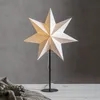 A white paper star lamp on a black stand, placed on a white surface with a gray background. Podgląd zdjęcia produktu