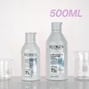 Two bottles of Redken shampoo are displayed on a reflective surface with beakers in the background. Text overlay indicates '500ML'. Produktbild-Vorschau