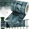 A roll of fence privacy screen with a stone pattern is shown, along with a section of fence already covered with the screen and some clips. Náhled obrázku produktu