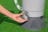 A person's hand is shown adjusting a clear plastic dial on a gray filter system, which is placed on a green, artificial grass surface. Produktbild-Vorschau