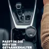 A person's hand wearing a sweater is visible on the right side of the image, reaching towards a car's center console. The console features a gear shifter, drive mode buttons (ECO, NORMAL, SPORT, EV), and a cup holder containing a black travel mug. Text ove Náhled obrázku produktu