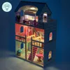 A detailed, illuminated dollhouse with furniture, displayed in a dark setting. Voir les images du produit