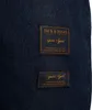 A close-up view of two dark blue fabric labels with text on a dark blue denim-like fabric. Produktbild-Vorschau