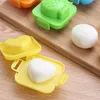 A close-up of colorful plastic molds for shaping food, like rice or eggs, on a wooden surface. Produktbild-Vorschau