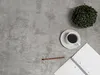 A top-down view of a desk setup with a plant, coffee cup, notebook, and pencil. Produktbild-Vorschau