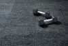Two dumbbells are placed on a grey carpeted surface. Produktbild-Vorschau