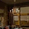 A rustic antler chandelier hangs in a living room with large windows overlooking a forest landscape. Náhled obrázku produktu