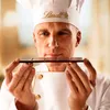 A chef in a white uniform and hat is holding a dark chocolate bar with chili. Produktbild-Vorschau
