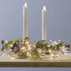 A decorative wreath with LED lights and two LED candles on a wooden surface. Produktbild-Vorschau