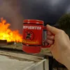 A hand holds a red firefighter mug in front of a large fire. Produktbild-Vorschau