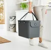 A person is holding a gray storage box with handles in a kitchen or utility room setting. Produktbild-Vorschau