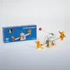 A wooden candle holder with figures on a seesaw, next to its packaging. Anteprima dell’immagine prodotto