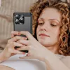 A woman with curly hair is lying down and looking at her phone. Produktbild-Vorschau