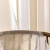 A close-up view of sheer curtains with a striped pattern, draped over a wooden furniture piece. Produktbild-Vorschau