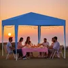People enjoying a meal under a blue canopy at sunset. Produktbild-Vorschau