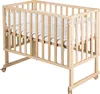 A wooden crib with white bedding and protective padding. Produktbild-Vorschau
