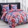 A neatly made bed with a floral patterned duvet and pillows. Náhled obrázku produktu