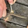 A close-up of a hand using a knife to strike a ferro rod, creating sparks. Produktbild-Vorschau