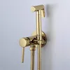 A close-up shot of a gold bidet sprayer and faucet mounted on a light gray wall. Anteprima dell’immagine prodotto