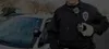 A police officer stands next to a police car, wearing a body camera. Náhľad obrázku produktu