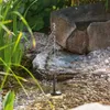 A small solar-powered fountain is operating in a garden pond with rocks and plants. Produktbild-Vorschau