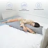 A woman is sleeping on a bed, hugging a long body pillow. Produktbild-Vorschau