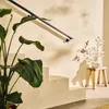 A modern staircase with a large plant and a small wooden stool with a vase of flowers. Podgląd zdjęcia produktu