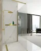 A modern bathroom with a gold shower fixture and a glass partition. Produktbild-Vorschau