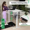 A woman is using a standing desk while on the phone and walking on a treadmill. The desk is shown in a home office setting with plants and a window in the background. Produktbild-Vorschau