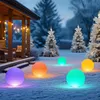 Outdoor scene at dusk or night with snow on the ground, featuring a house porch with string lights and several illuminated spherical garden lights in various colors. Produktbild-Vorschau