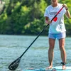 A person is paddleboarding on a lake, holding a paddle. Produktbild-Vorschau