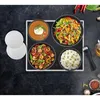 A top-down view of a cooking set with four bowls of food arranged on a black stovetop. Voir les images du produit