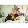 A mother and child are reading a book together on a bed, surrounded by stuffed dinosaur toys. Anteprima dell’immagine prodotto