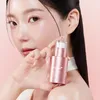 A woman holds a pink serum bottle against a pink background. Produktbild-Vorschau