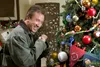 A man is shown laughing while looking at a decorated Christmas tree. Náhled obrázku produktu