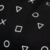 A close-up of a black fabric with a pattern of white geometric shapes, resembling PlayStation controller buttons. Anteprima dell’immagine prodotto