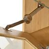 A close-up view of a metal hinge mechanism attached to a wooden cabinet, likely part of a furniture piece like a sideboard or display cabinet. Anteprima dell’immagine prodotto