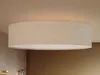 A close-up shot of a round LED ceiling light with a linen fabric shade, mounted on a beige ceiling. Produktbild-Vorschau