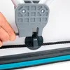 A hand is shown adjusting a rope mechanism on a white surface, with a blue and black striped edge visible at the bottom. Podgląd zdjęcia produktu
