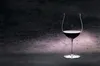 A single glass of red wine on a dark, textured background. Podgląd zdjęcia produktu