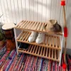 A shoe rack with shoes, a hat, and a drum next to it, placed on a colorful rug in front of a white slatted wall. Podgląd zdjęcia produktu